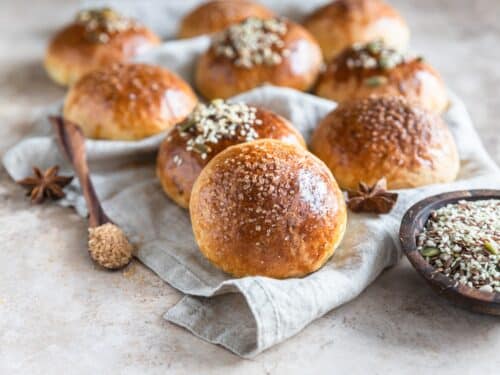 Frische hausgemachte Kürbisbrötchen mit braunem Zucker oder Samen, heller Betonhintergrund. Herbstbäckerei.